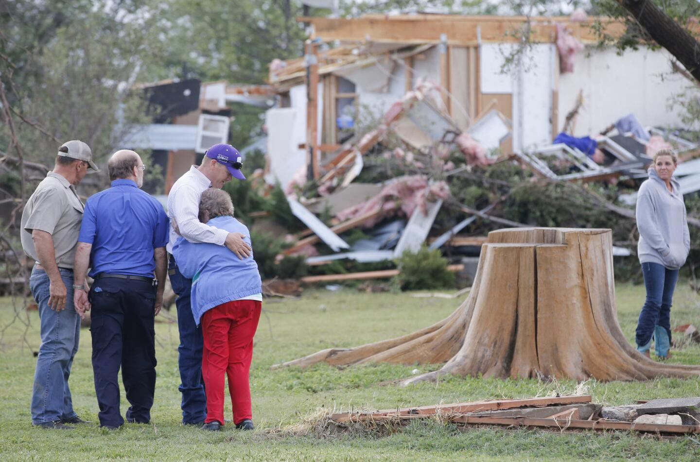 Charmaine Foraker is hugged by her son Harlan, as she and her other son Craig Foracker, second from left, arrive at the scene of the family farmstead near Bentley, Kan., that was destroyed by a tornado Wednesday, May 6, 2015.