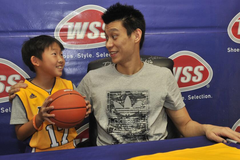 Lakers guard Jeremy Lin meets with a young fan while signing autographs in Lincoln Heights on Saturday.