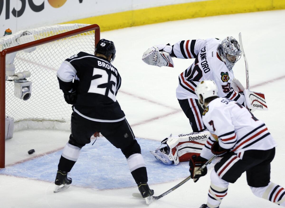 Kings captain Dustin Brown, left, scores past Chicago Blackhawks goalie Corey Crawford and defenseman Brent Seabrook during Game 4 of the Western Conference finals at Staples Center.