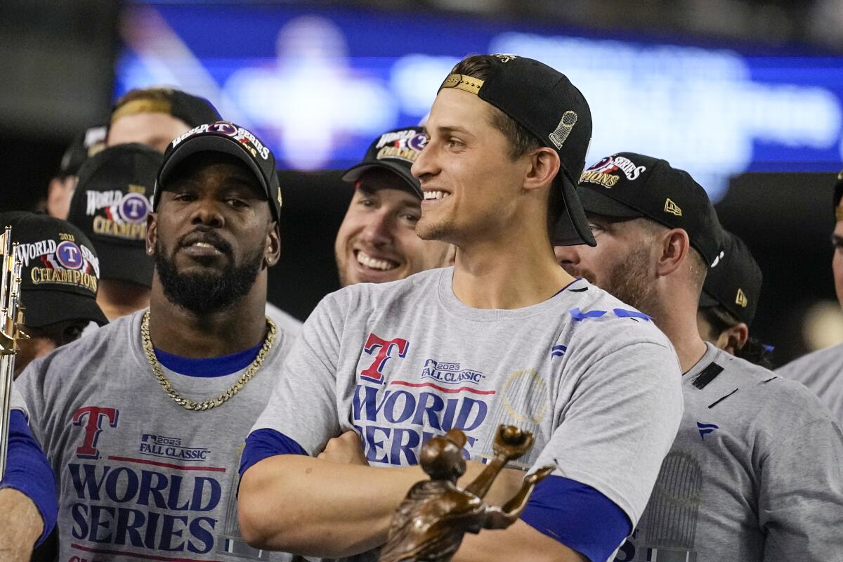 Rangers shortstop Corey Seager stands behind the World Series MVP award with his arms folded and hat on backward.