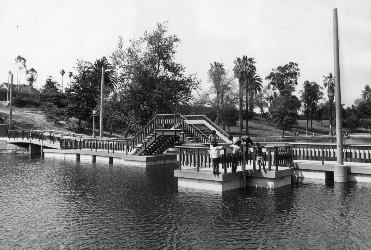April 25 1971: Children climb outside the railing while crossing the new pontoon bridge on the refilled lake in Boyle Heights' Hollenbeck Park.