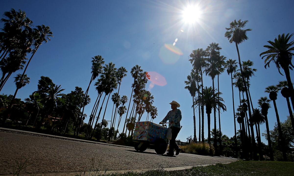 An ice cream vendor pushes a cart on the sidewalk that rings Echo Park Lake in Echo Park.