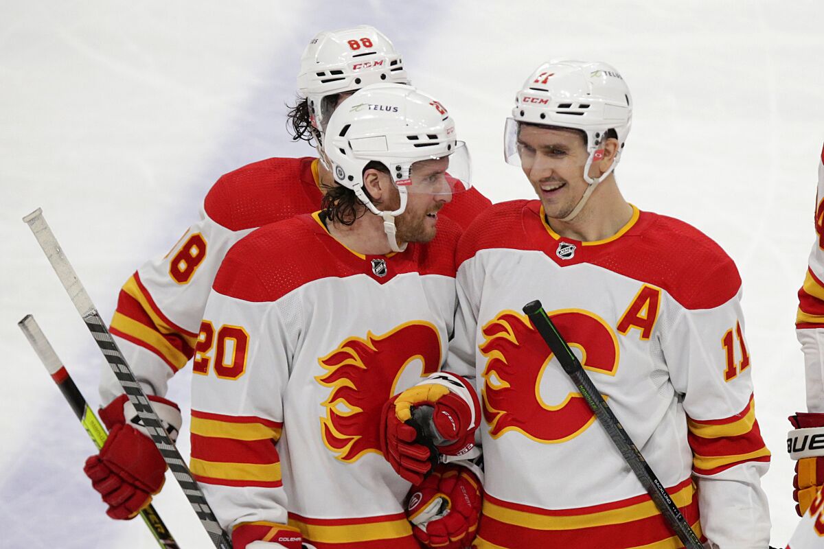 Calgary Flames center Mikael Backlund (11) receives congratulations from Blake Coleman (20) and Andrew Mangiapane (88) after scoring against the Minnesota Wild during the third period of an NHL hockey game Tuesday, March 1, 2022, in St. Paul, Minn. (AP Photo/Andy Clayton-King)