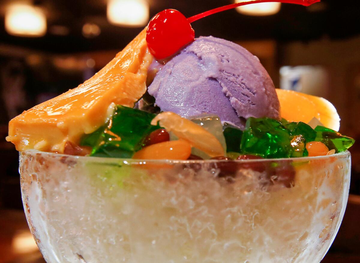 A close up of a bowl containing a sweet dessert with a cherry on top.