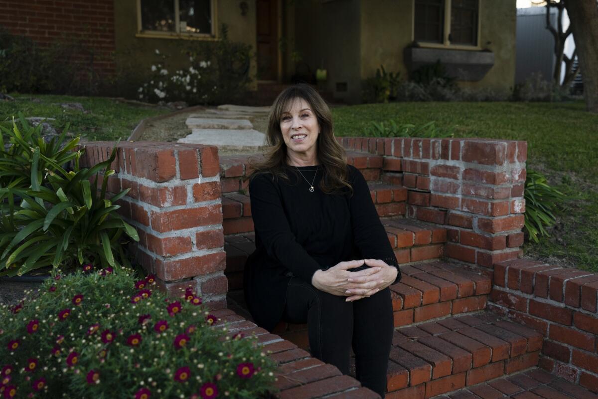 A woman sits on steps outside her home in Los Angeles.