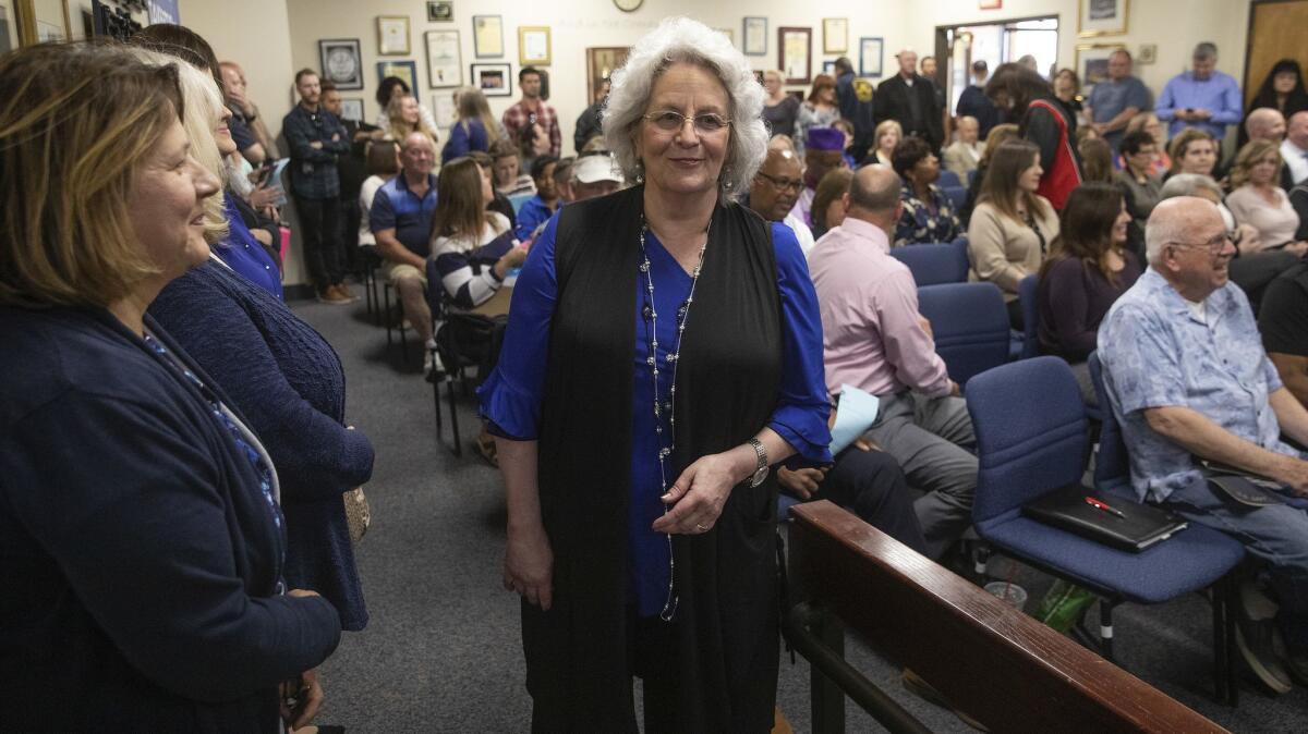Antelope Valley Union High School District trustee Jill McGrady, center, makes her way to her seat before the start of a special board meeting April 18.