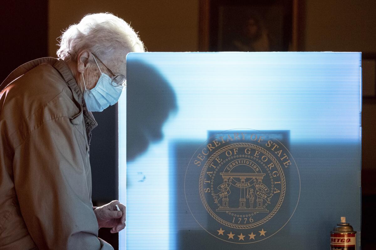 A woman stands at a voting station marking her ballot.