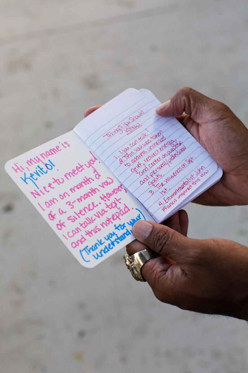 Kevito Clark holds up a notepad he uses to communicate with people that has pre-written pages explaining why he decided not to speak for three months.