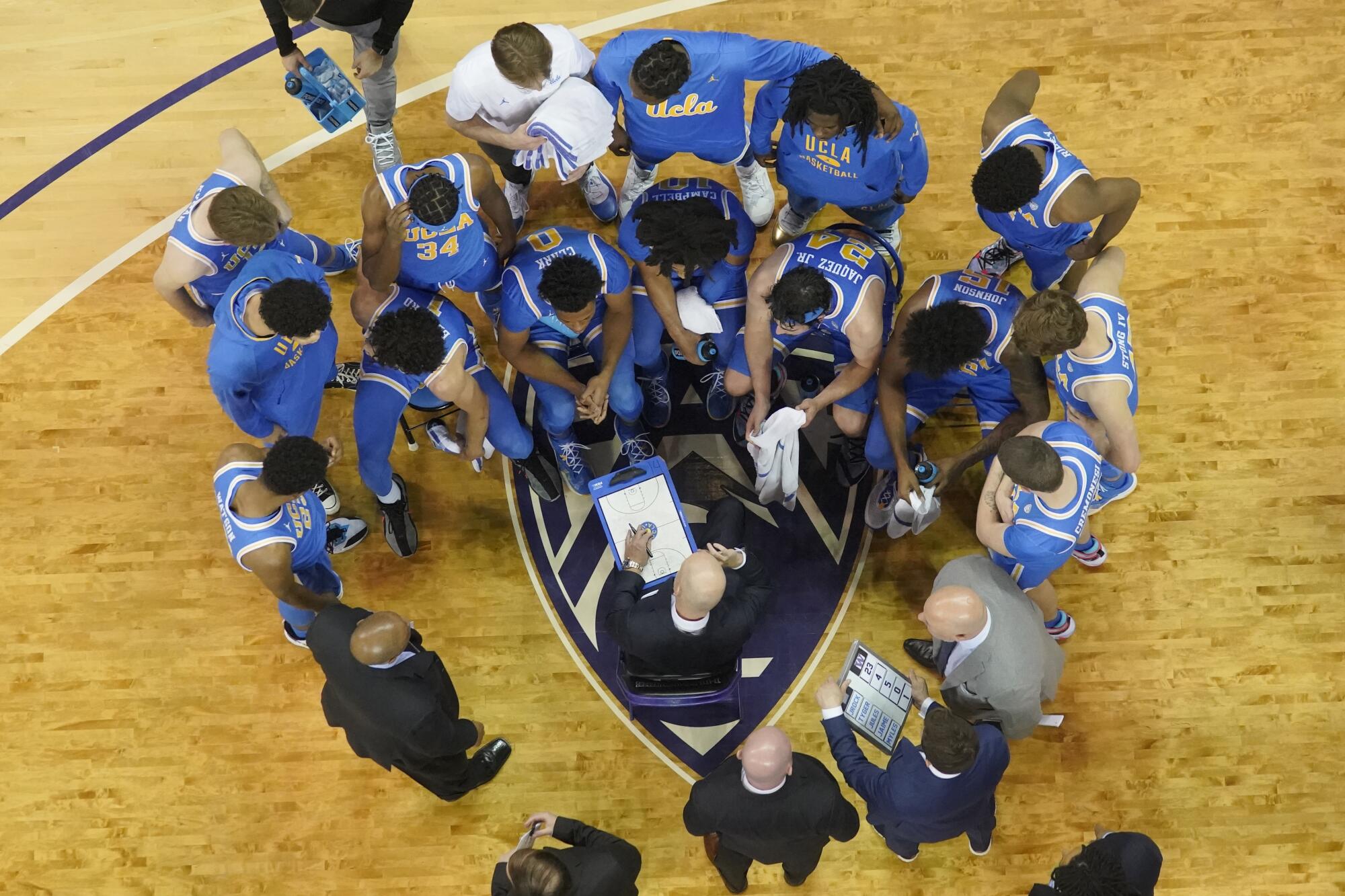 UCLA coach Mick Cronin, center, talks to his team during a time out 