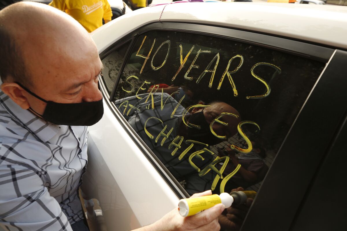 A man writes on the window of a car: "40 years serving at Chateau"