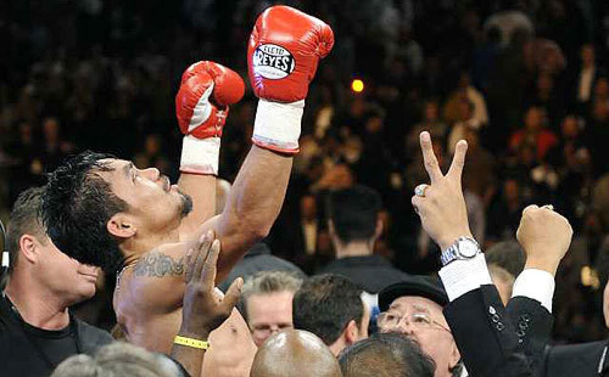 Manny Pacquiao is lifted above the ring after defeating Oscar De La Hoya in eight rounds Saturday night at the MGM Grand Garden Arena in Las Vegas.