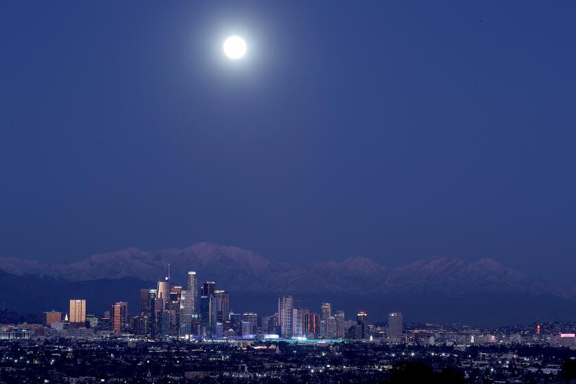 LOS ANGELES, CA. - DEC. 29 2020. A full moon rises over the snow-capped San Gabriel Mountains and the skyline of downtown Los Angeles on Tuesday, Dec. 29,2020. (Luis Sinco/Los Angeles Times)