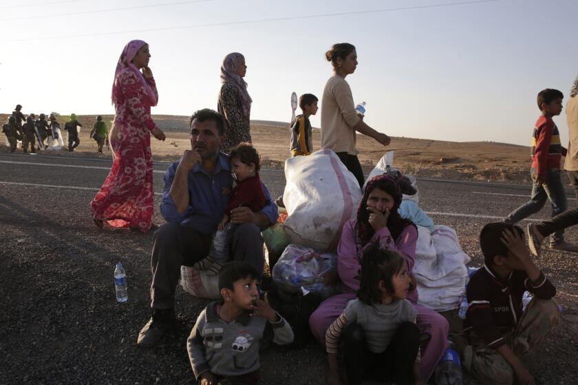 Kurdish refugees wait by the side of the road Oct. 5 near Suruc, Turkey, after their arrival from Kobani, Syria. Fighting between Syrian Kurds and the militants of Islamic State has intensified in Kobani.