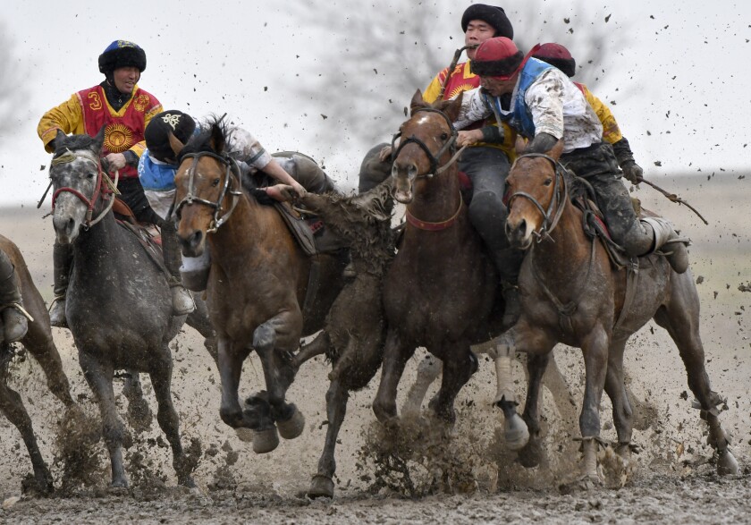 Riders compete during a kok boru, also called ulak tartysh, a traditional game in which players on horseback manoeuvre with a goat's carcass and score by putting it into the opponents' goal outside Sokuluk village, 20 km (12,5 miles) west of Bishkek, Kyrgyzstan, Tuesday, March 30, 2021. (AP Photo/Vladimir Voronin)