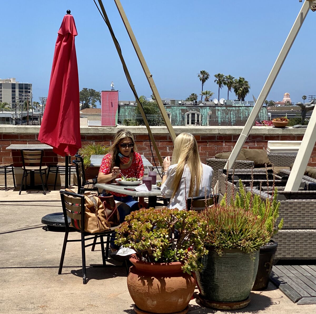 Customers eat at Trilogy Sanctuary's newly reopened rooftop cafe May 22 in La Jolla. Tables are spaced 10 feet apart for social distancing.