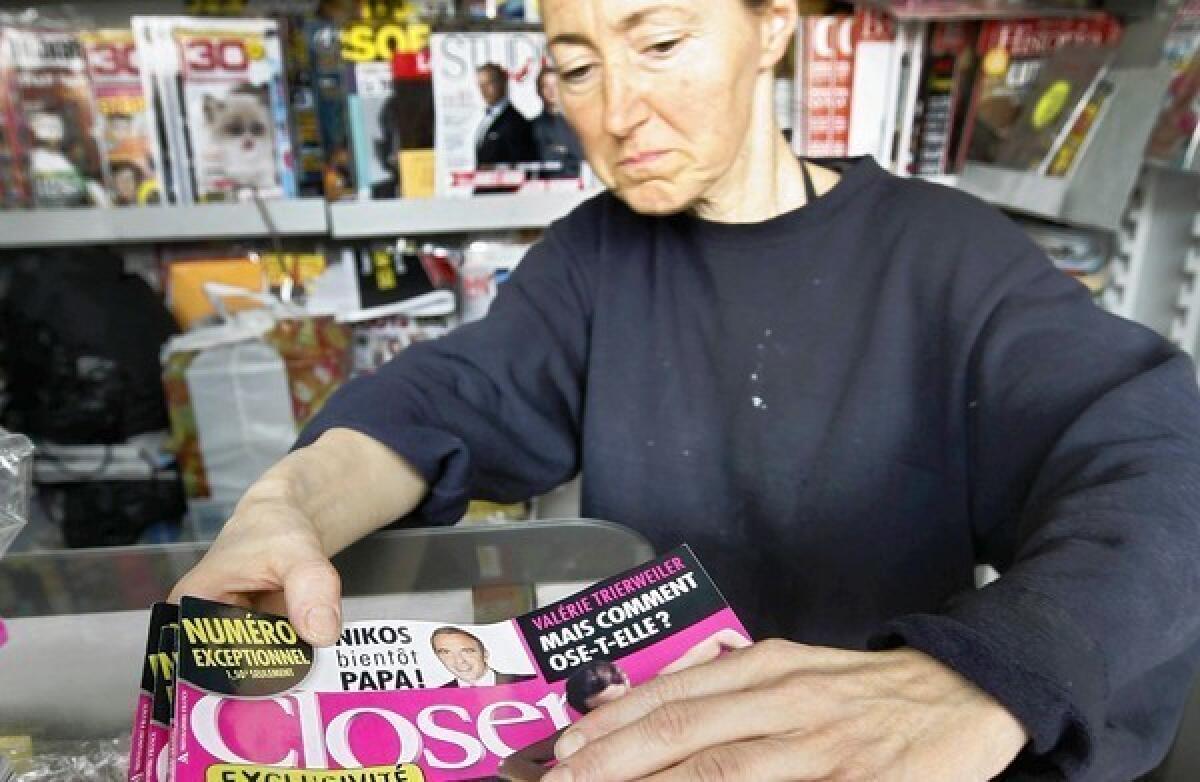A newsstand clerk checks copies of Closer magazine Tuesday in Nice, southern France.