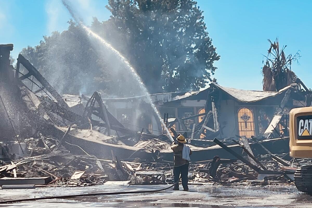A firefighter douses the remains of Victory Baptist Church, which was destroyed by a fire