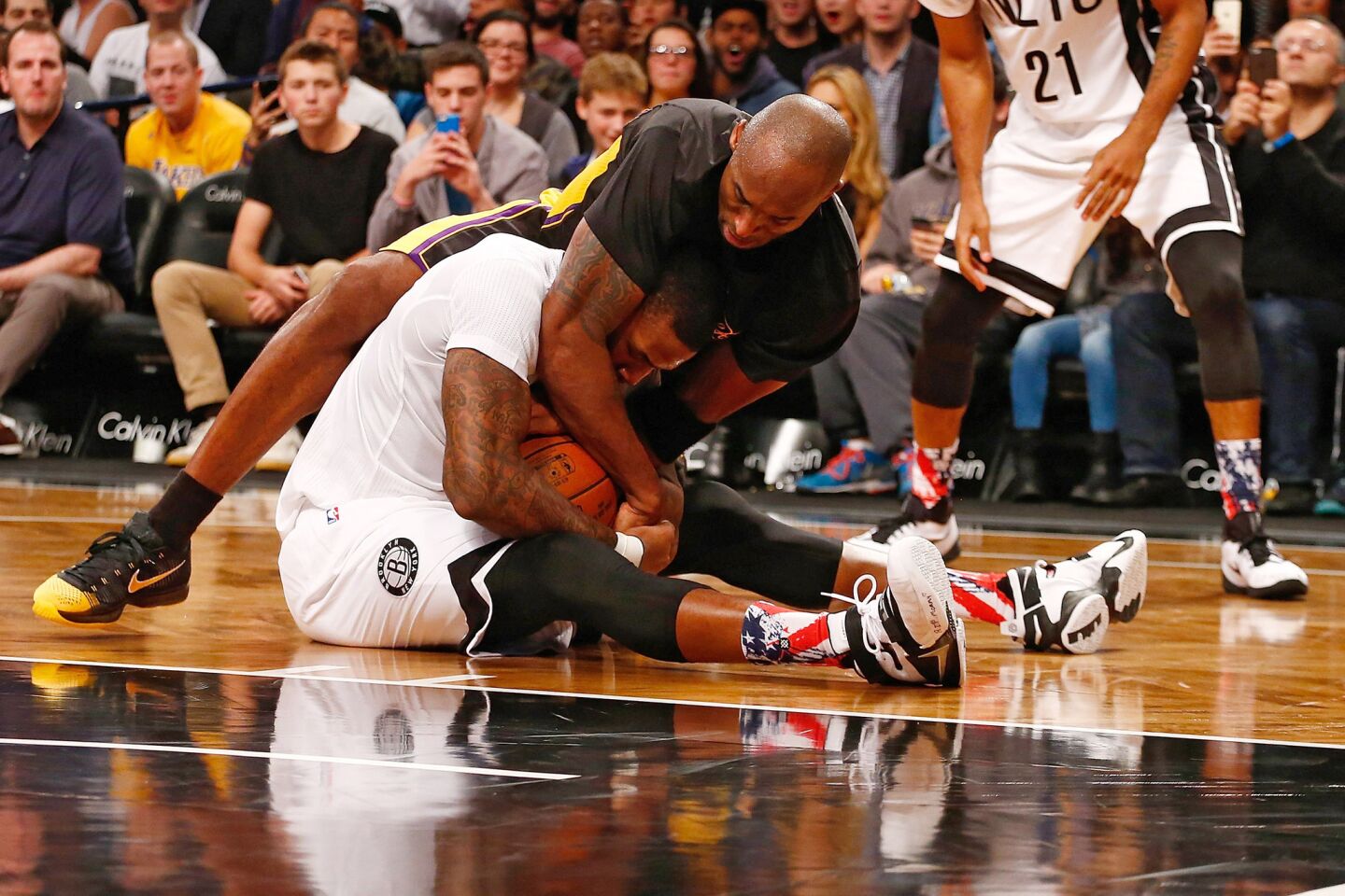 Los Angeles Lakers' Kobe Bryant and Brooklyn Nets' Thomas Robinson fight for the ball on Friday.