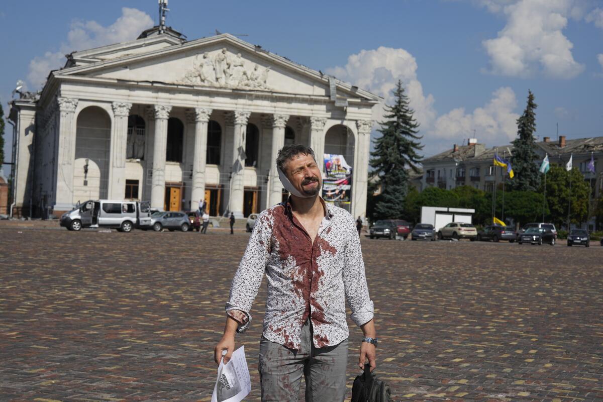 An injured man, with dried blood covering much of his dress shirt