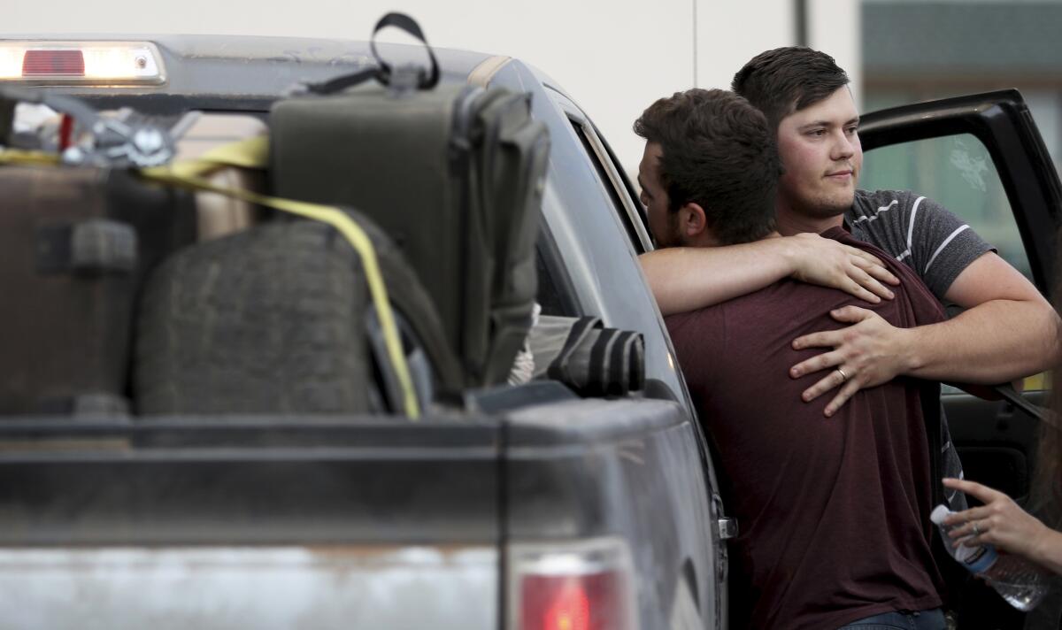 Cole Langford, left, and Hayden Spenct of the Mormon colony in La Mora, Mexico, hug at a gas station Nov. 9 in Douglas, Ariz. Members of the colony began leaving Mexico this weekend.