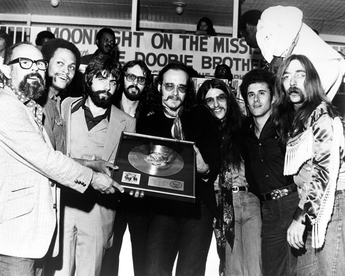A man presents a gold record to a rock band.