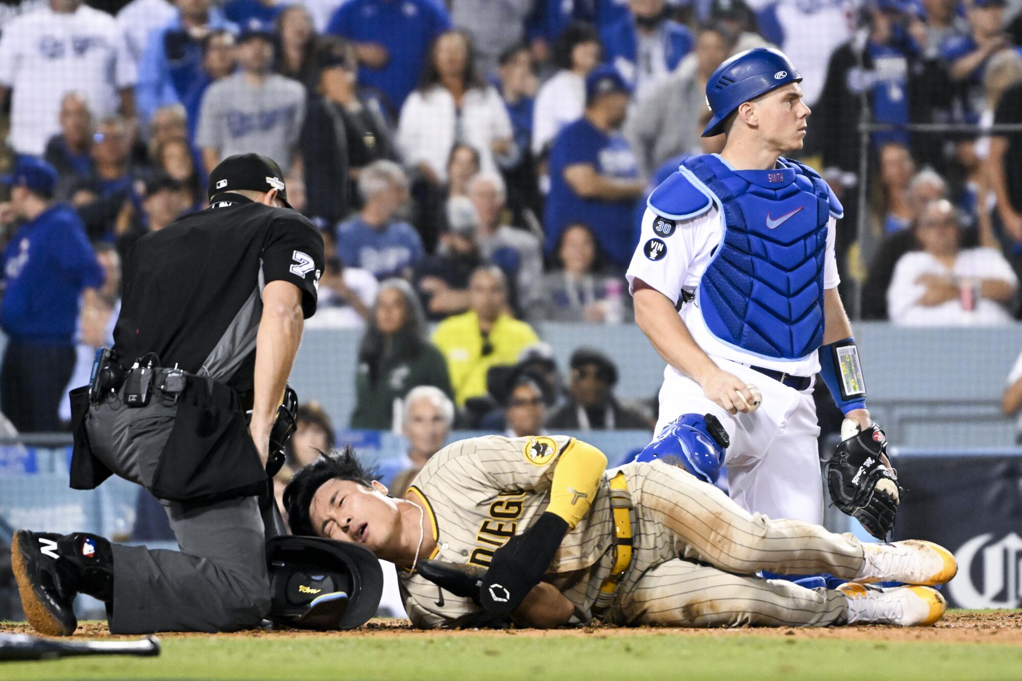 Padres' Ha-Seong Kim grimaces after sliding past Dodgers catcher Will Smith to score a run.