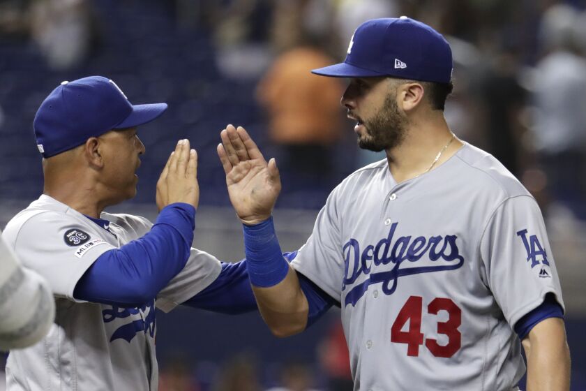 Los Angeles Dodgers manager Dave Roberts, left, high-fives Edwin Rios (43) after defeating the Miami Marlins in a baseball game, Wednesday, Aug. 14, 2019, in Miami. (AP Photo/Lynne Sladky)