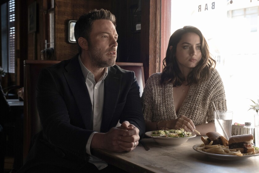 A man and a woman sit side-by-side at a dining room table.