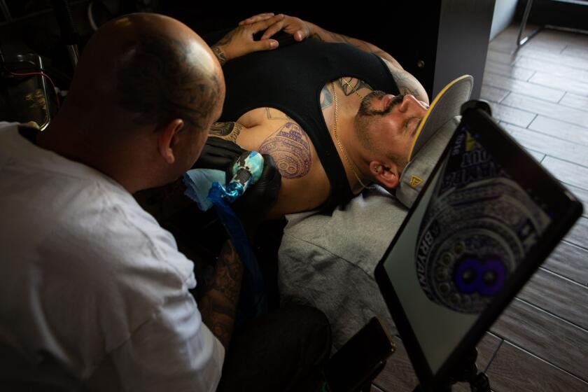 Los Angeles, CA., February 5, 2020 — Tattoo Artist, Jose Guijosa, 34, of Pomona tattoos custom artwork on Anthony Lozano, 33, of Pomona on Wednesday, February 5, 2020 in Los Angeles, California. Lozano is one of many of Guijosa’s clients paying tribute to the late Kobe Bryant with ink. Tattoo artists are seeing an increase in business since Bryant’s death, fans in the region are lining up for tattoos centered around Bryant. (Jason Armond / Los Angeles Times)