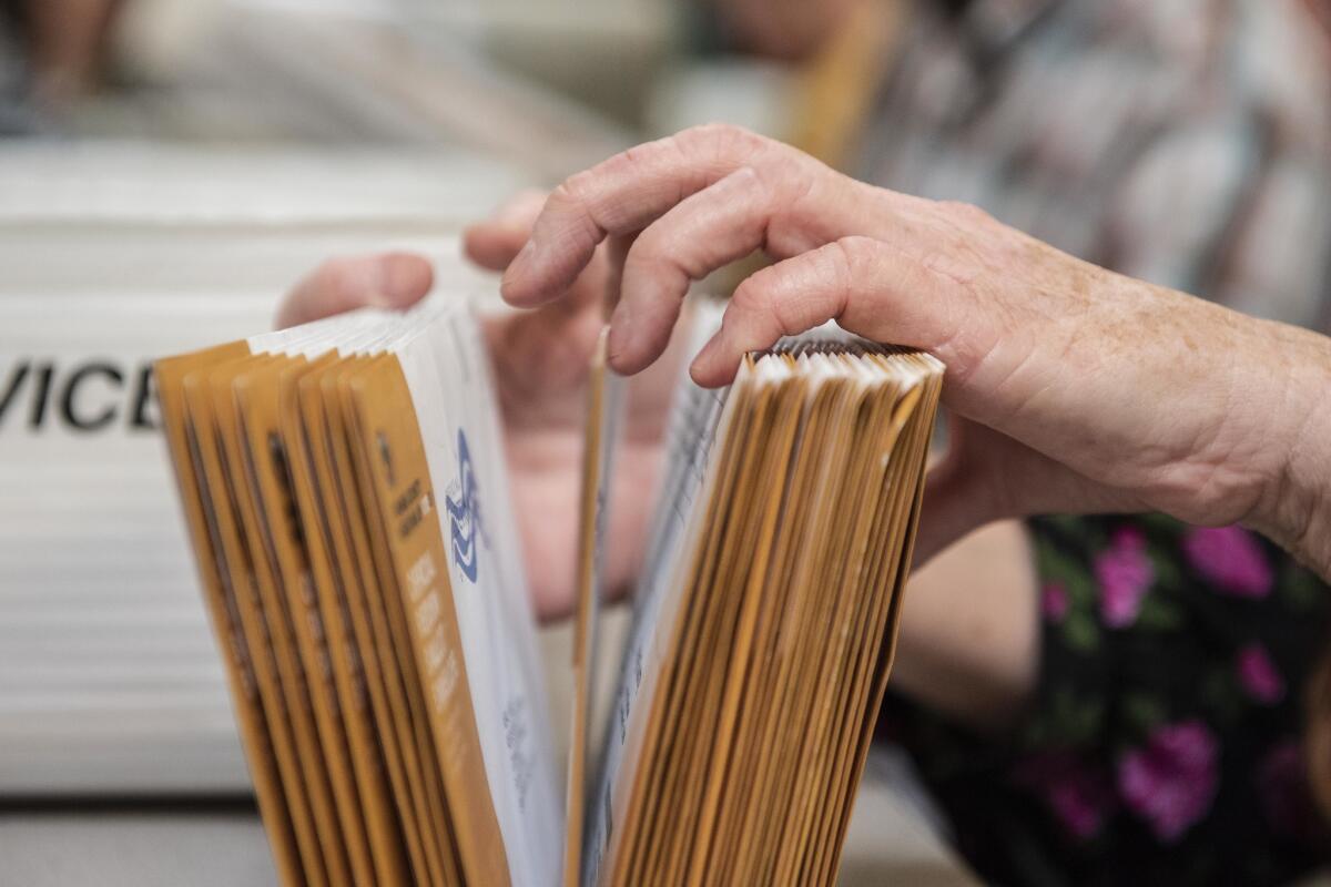 An employee of the Orange County Registrar of Voters sorts through mail-in ballots in November 2018 in Santa Ana.