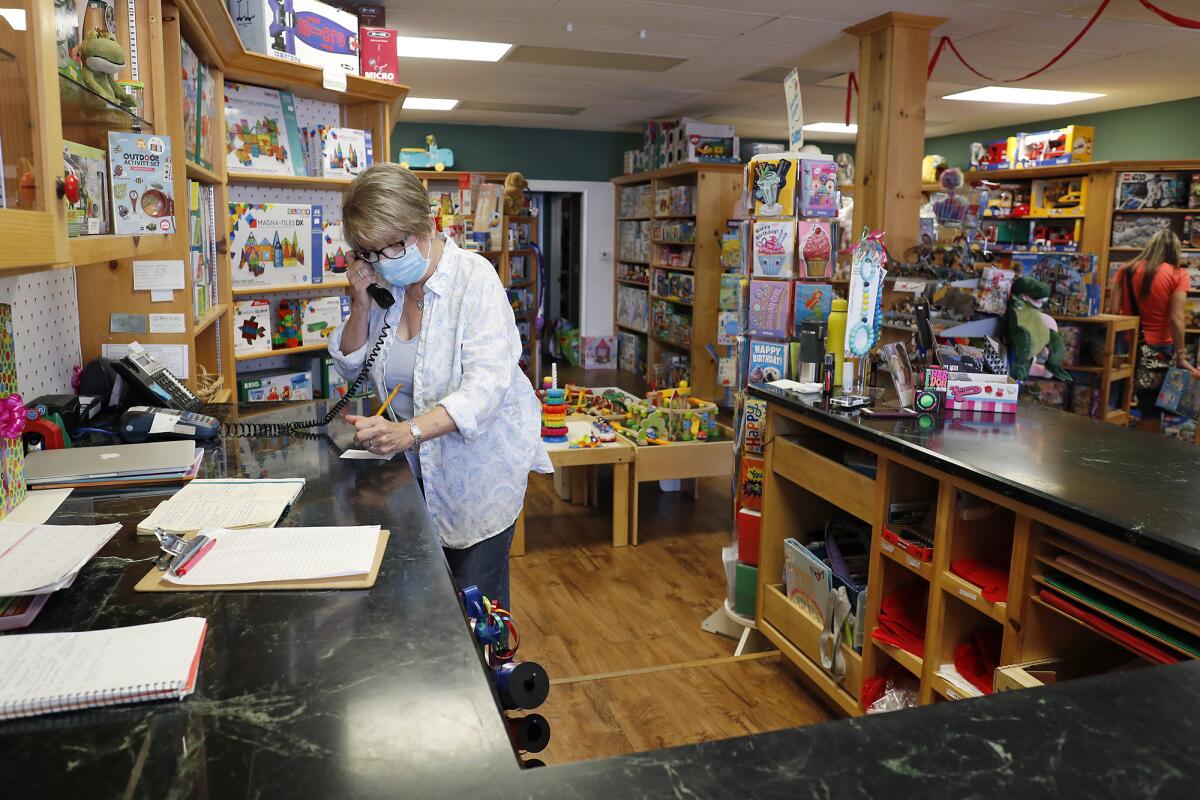 Owner Erin Kelly takes an order at her toy store, the Wee Loft in Corona del Mar, on Friday, May 8, the day Gov. Gavin Newsom allowed businesses such as toy stores, florists, clothing stores and bookstores to reopen for curbside pickup.