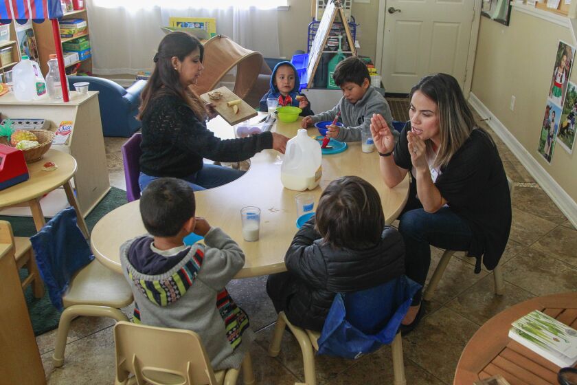 Teacher Elizabeth Garza (left) and YMCA Childcare Resource Service quality support specialist Marlene Fuentes (right) work with children during snack time on May 1, 2019 in Vista, California.