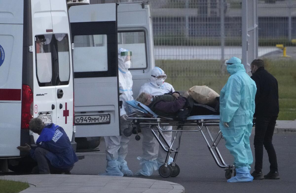 Personal médico traslada en camilla a un posible paciente de coronavirus en un hospital de Kommunarka