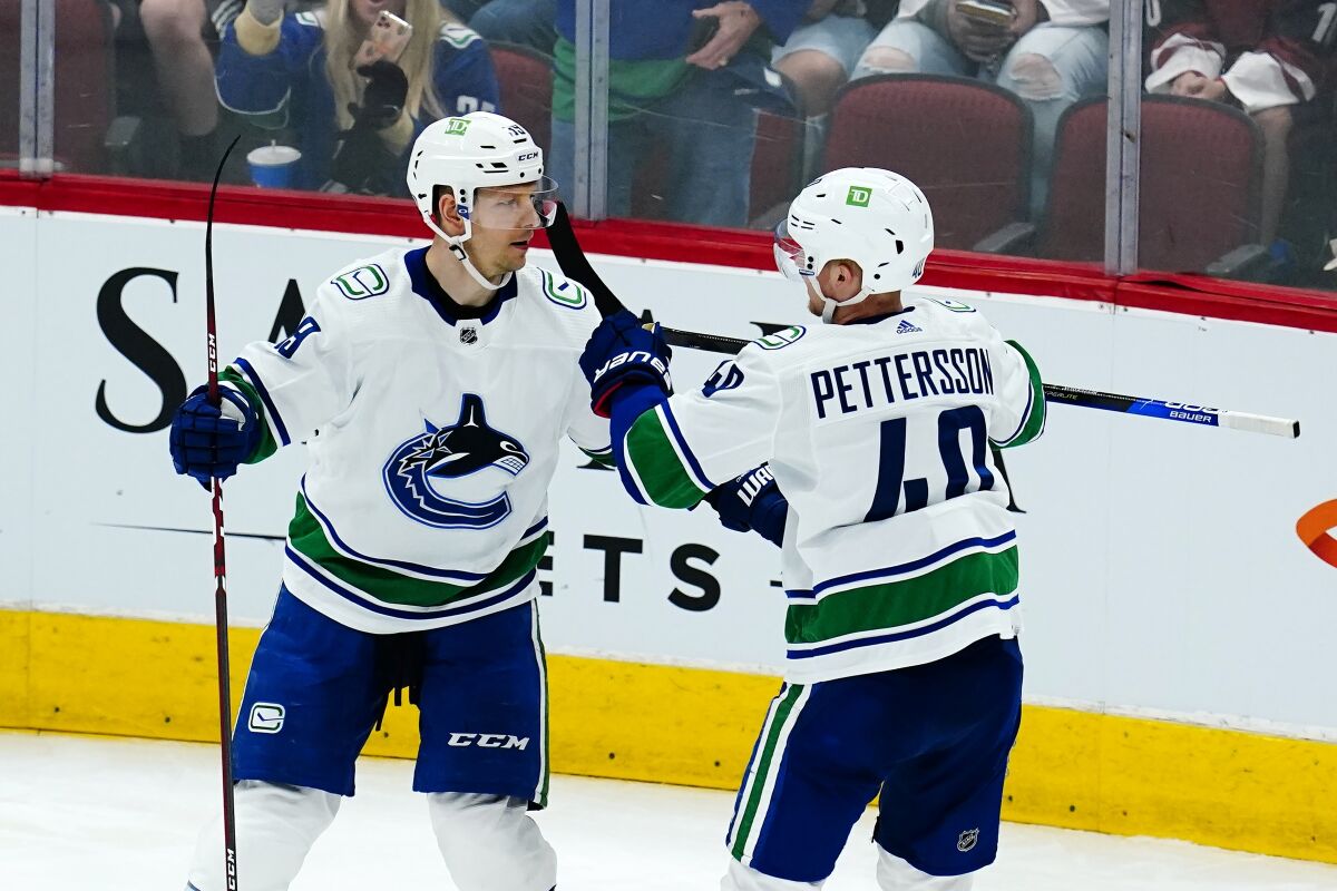 Vancouver Canucks center Elias Pettersson (40) celebrates his goal against the Arizona Coyotes with Canucks right wing Alex Chiasson, left, during the second period of an NHL hockey game Thursday, April 7, 2022, in Glendale, Ariz. (AP Photo/Ross D. Franklin)