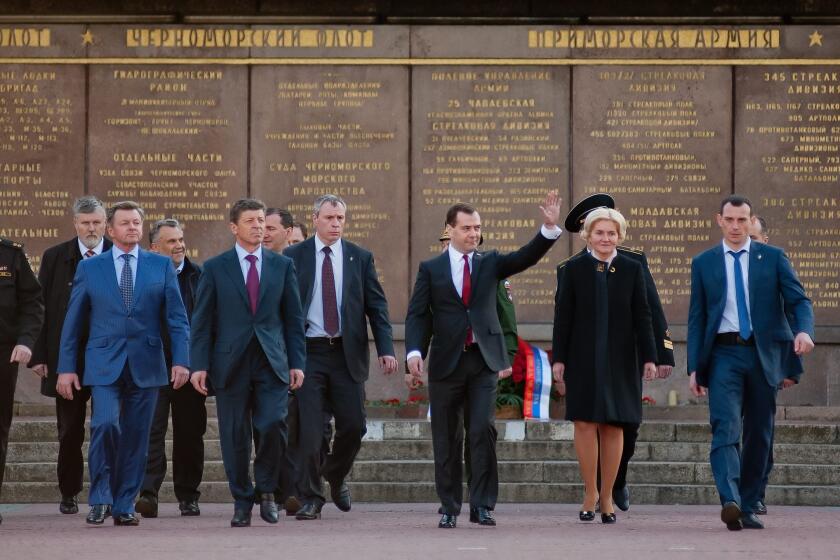 Russian Prime Minister Dmitry Medvedev waves as he leads a delegation of Russian government officials on a visit to Crimea, visiting the World War II Memorial to the Heroic Defense of Sevastopol.