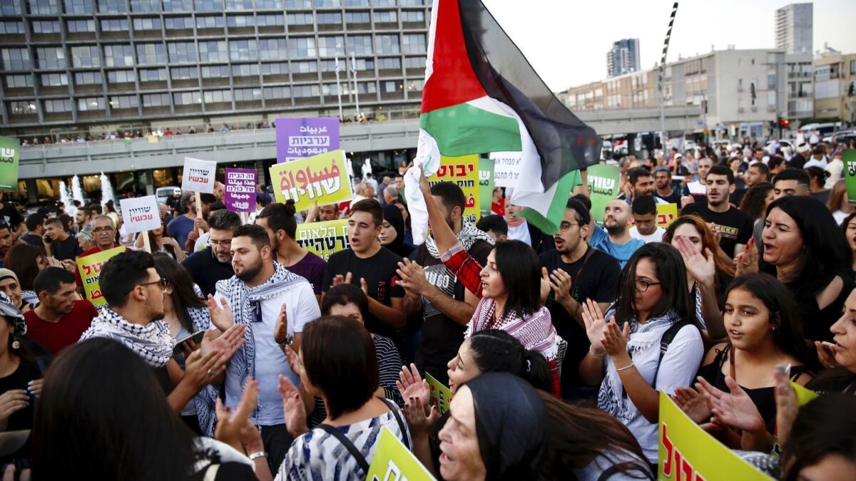 Israeli Arabs hold a Palestinian flag during a protest against the Jewish nation law in Tel Aviv, Israel, Saturday, Aug. 11, 2018. The recently passed law enshrines Israel's Jewish character and downgrades the standing of Arabic from an official to a "special" language.