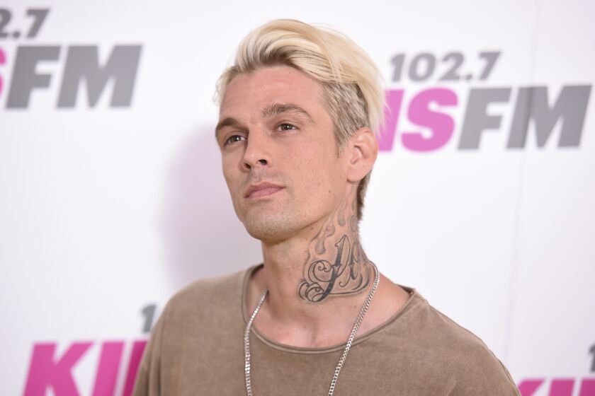 A blond man with a neck tattoo looks up