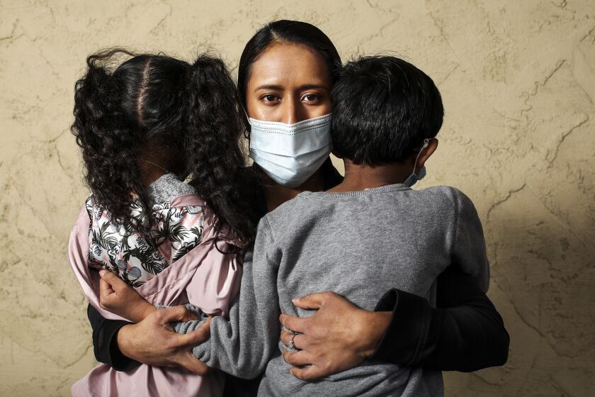 Karla Barrera, 28, holds onto her children, ages 4 and 6, outside Ralphs where she works as a deli manager on April 9, 2020, in Los Angeles, California. She has not felt safe at work ever since the pandemic began and several Ralphs in the L.A. have been fined for failing to protect workers from exposure to coronavirus. "If the company preps us and gives us the right equipment, we wouldn't be so scared," she said.