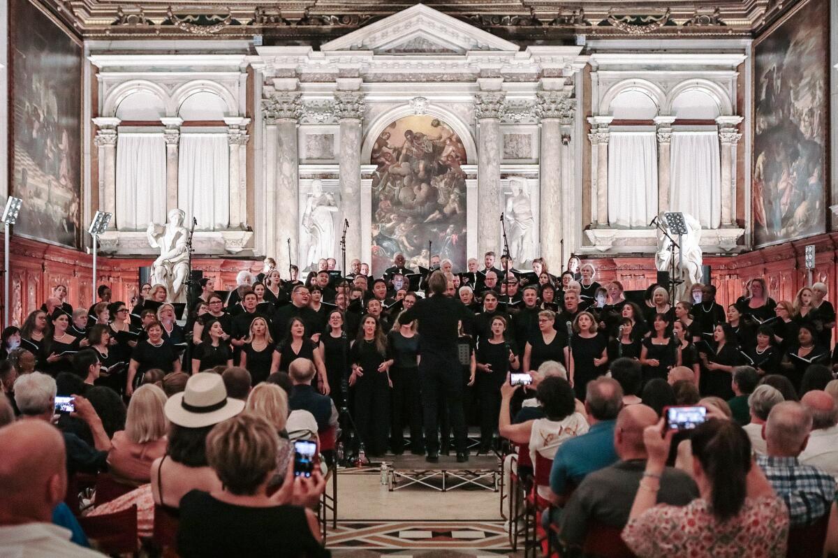 Two choirs perform together inside an old building in Italy.