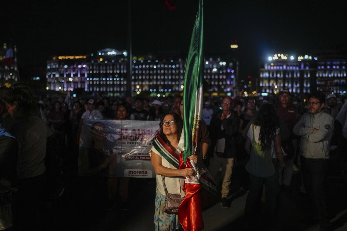 A woman holds a large Mexican flag.