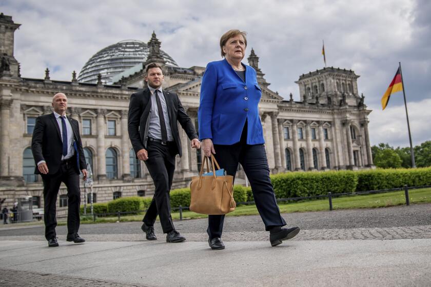 Chancellor Angela Merkel (CDU) walks to the Chancellery on foot, accompanied by her bodyguards, after the government questioning in the Bundestag in Berlin, Germany, Wednesday, May 13, 2020. In the 159th session of the German Bundestag, besides the government questioning, discussions about foreign missions of the Bundeswehr are on the agenda. (Michael Kappeler/dpa via AP)
