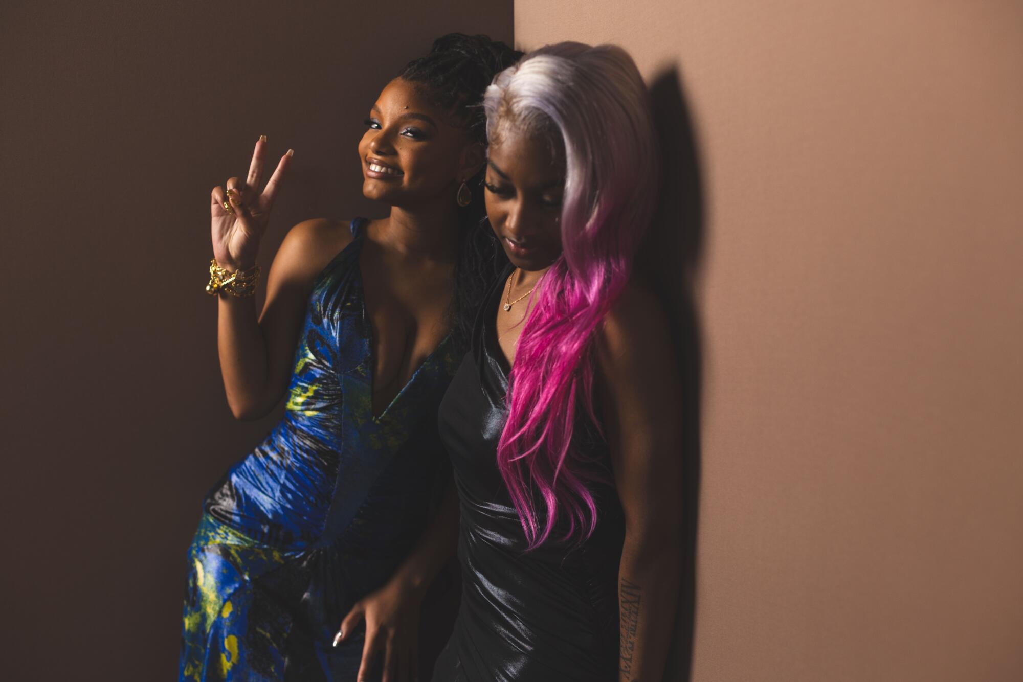 Halle Bailey, in a blue dress, stands next to Tiarra Granberry whose hair shades from silver to pink.