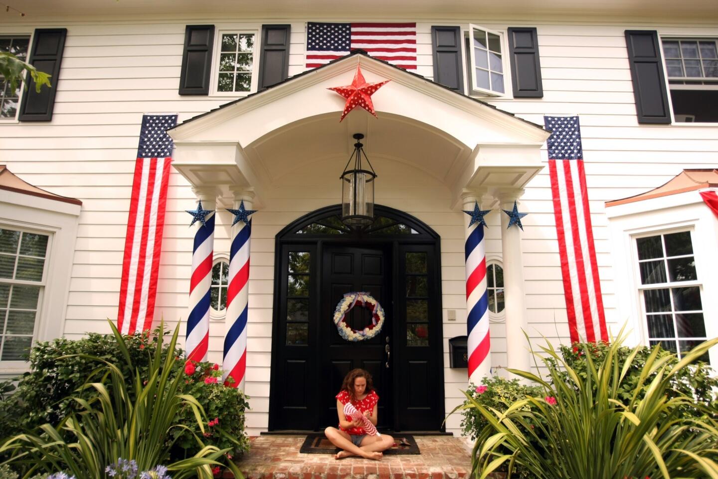 Molly Mercer, 21, works on Fourth of July decorations in front of her home. The house was awarded first place in Pacific Palisades' hotly contested home decorating competition this year.