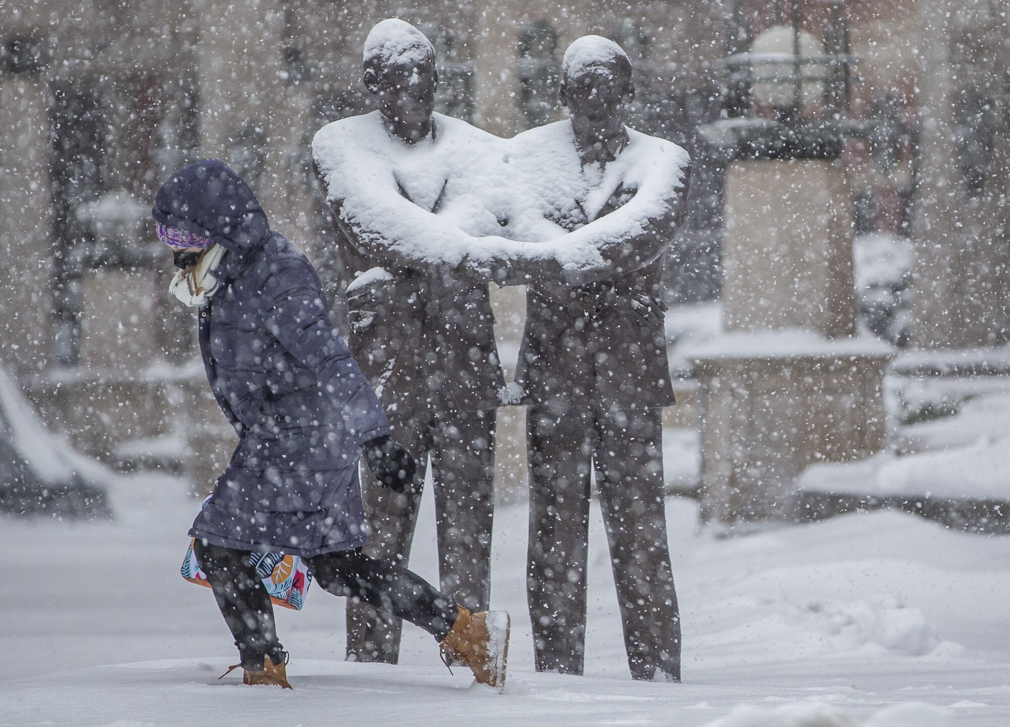 A person walks by a statue of Dr. Martin Luther King Jr. and Father Theodore Hesburgh, along South Main Street