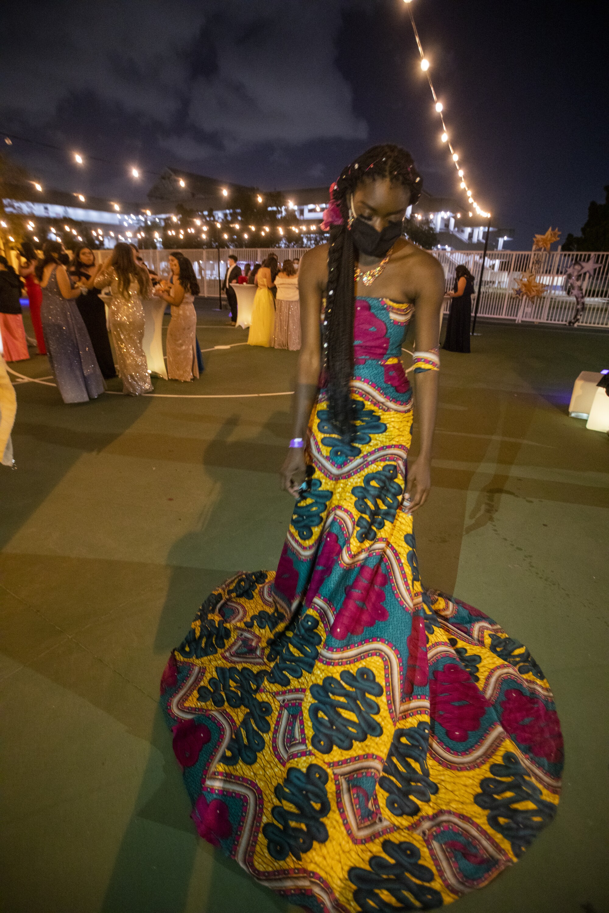 A teen in a long gown and a face mask