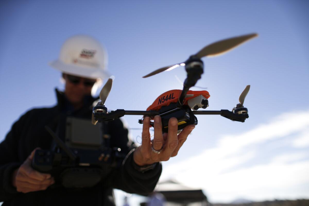 In this Oct. 16, 2014 file photo, former Navy helicopter pilot and San Diego Gas & Electric unmanned aircraft operator Teena Deering holds a drone as it is prepared for takeoff near Boulevard, Calif.