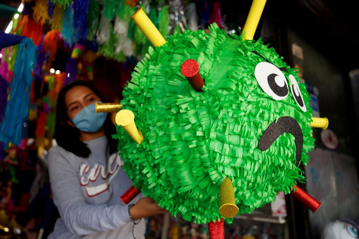  una trabajadora sosteniendo una piñata alusiva al coronavirus