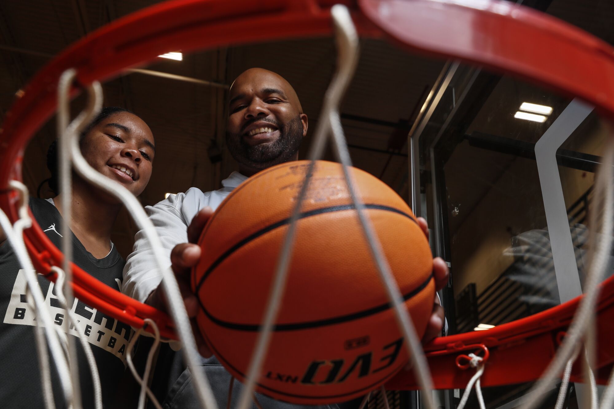 A man and daughter pose near basketball hoop.