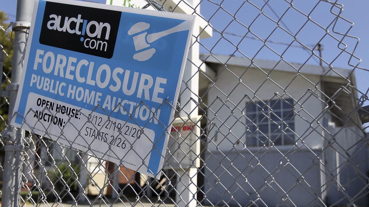 A foreclosure sign hangs on a fence in front of a foreclosed home in Richmond, Calif.