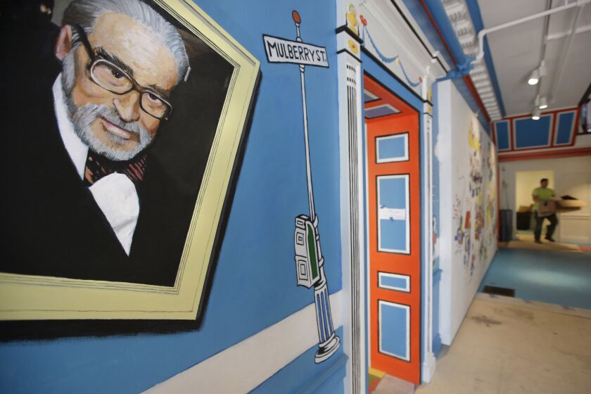 FILE - In this May 4, 2017, file photo, a mural that features Theodor Seuss Geisel, left, also known by his pen name Dr. Seuss, covers part of a wall near an entrance at The Amazing World of Dr. Seuss Museum, in Springfield, Mass. Dr. Seuss Enterprises, the business that preserves and protects the author and illustrator's legacy, announced on his birthday, Tuesday, March 2, 2021, that it would cease publication of several children's titles including "And to Think That I Saw It on Mulberry Street" and "If I Ran the Zoo," because of insensitive and racist imagery. (AP Photo/Steven Senne, File)